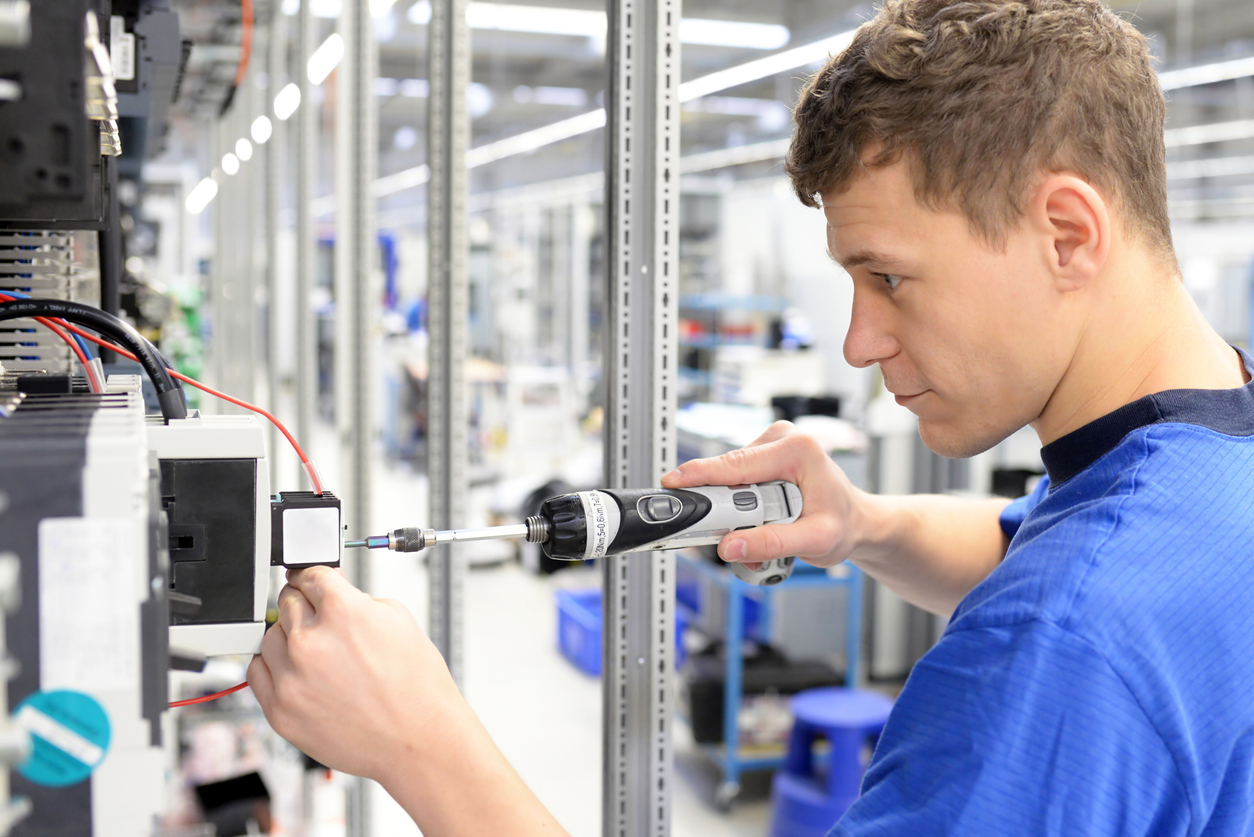 Junger Mann in einer industriellen Werkstatt arbeitet an der Elektronik